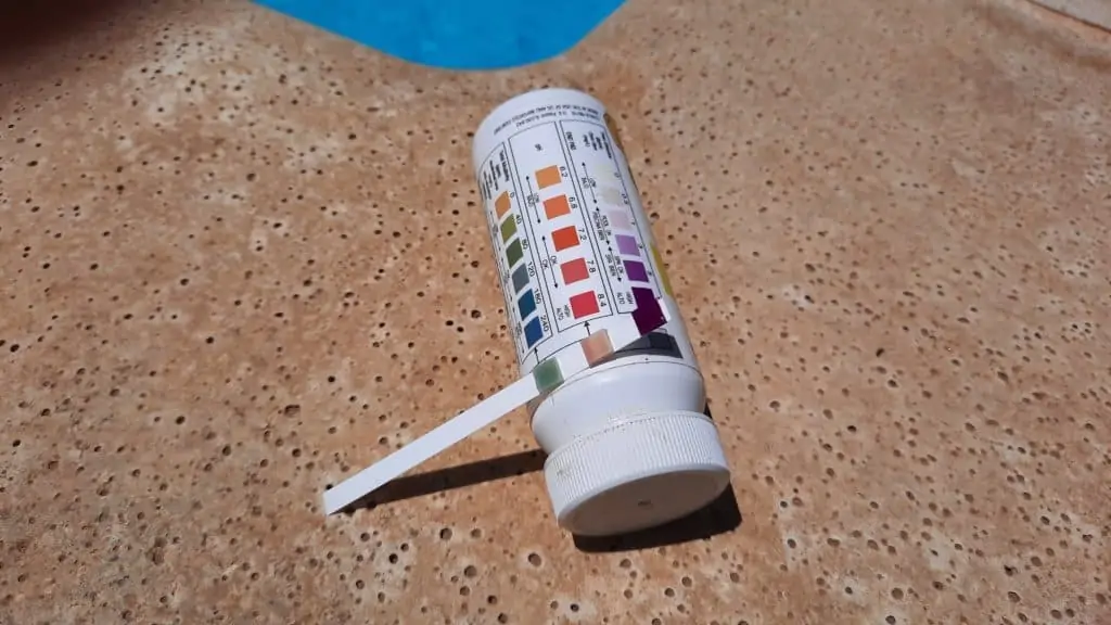 Pool test strip next to a swimming pool