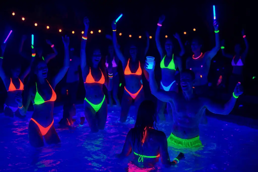A lively nightime pool party with UV lights, neon bikinis and other glow in the dark items